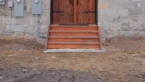 A stone building with a wooden door, a covered entrance, and a small set of steps leading up to the door. - The Scandinavian East Hall—Near Anthony Lakes! (North Powder)