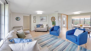 A spacious living room with a sofa, two armchairs, a dining table with chairs, and a large window providing natural light. - Coastal Oasis ~  Beaches, Parks, Shopping & Entertainment, Pet Friendly (Venice)