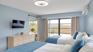 A bedroom with two beds, a TV, a dresser, and a window with curtains. - Coastal Oasis ~  Beaches, Parks, Shopping & Entertainment, Pet Friendly (Venice)