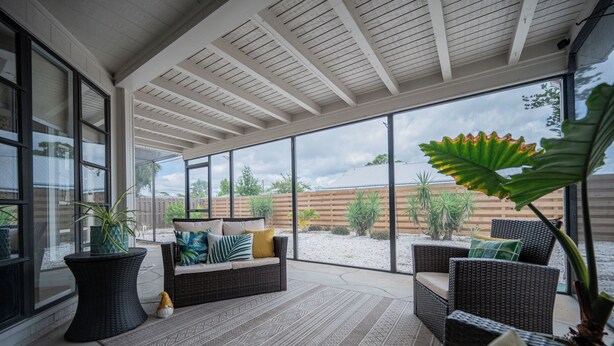 A covered patio area with wicker furniture, a large potted plant, and a view of the backyard. - Coastal Oasis ~  Beaches, Parks, Shopping & Entertainment, Pet Friendly (Venice)