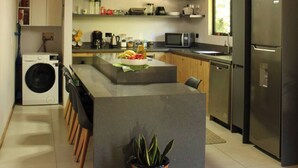Una cocina moderna con una isla central, techo de madera y electrodomésticos integrados.