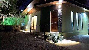 Una casa moderna con una entrada bien iluminada, ventanas grandes y un pequeño porche.