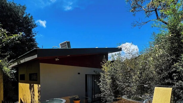 Una casa moderna con terraza de madera, jacuzzi y una silla.