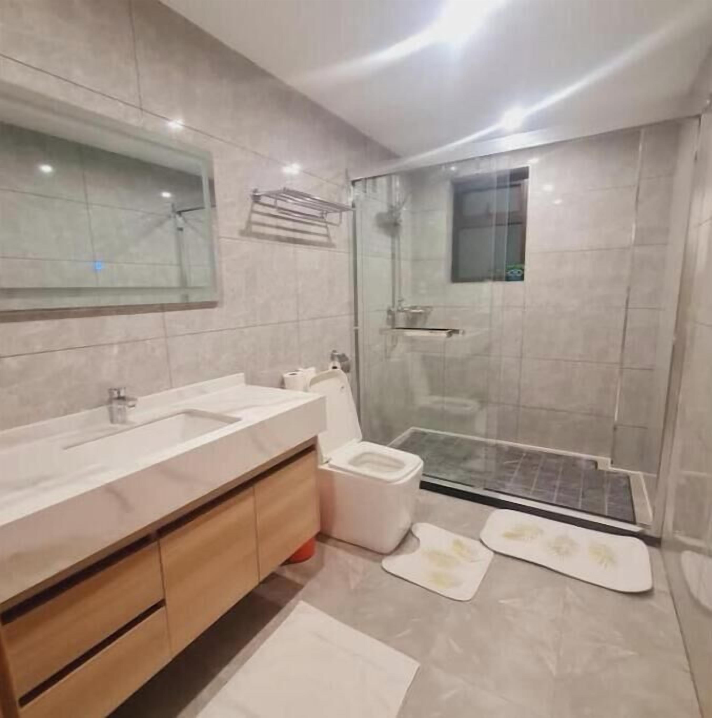 Ein modernes Badezimmer mit großem Spiegel, zwei Waschbecken, Toilette und einer Duschkabine.