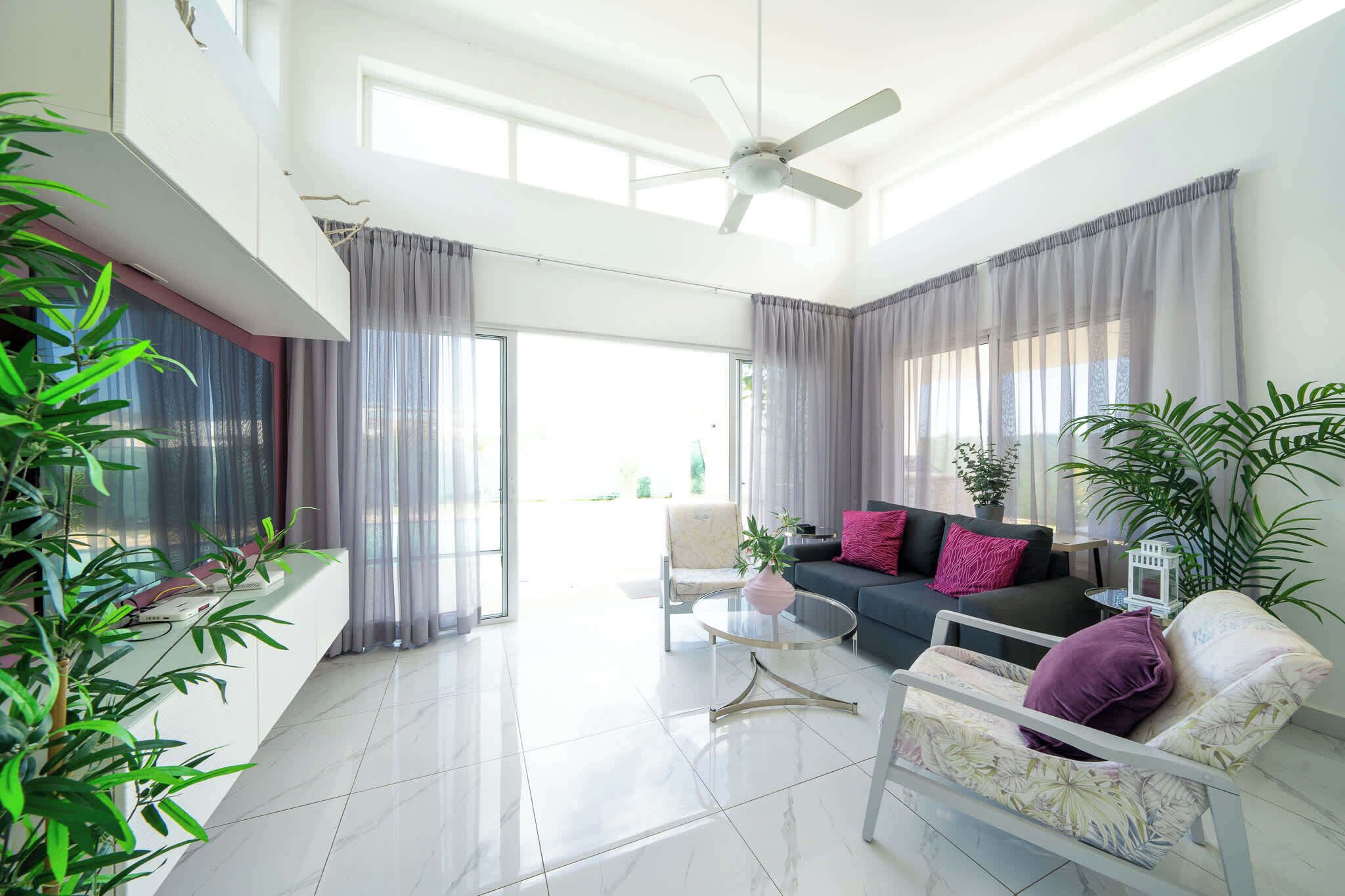 A spacious living area with a modern sofa, a round coffee table, and a ceiling fan.