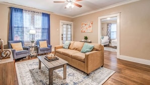 A living room with a beige sofa, two armchairs, a coffee table, and a ceiling fan. - Avalon Nest - Both Units (Memphis)