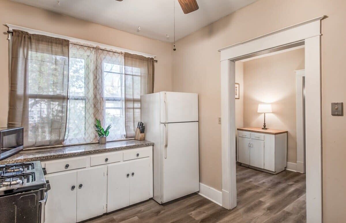 A compact kitchen with a refrigerator, microwave, and gas stove.