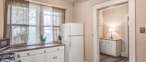 A compact kitchen with a refrigerator, microwave, and gas stove.