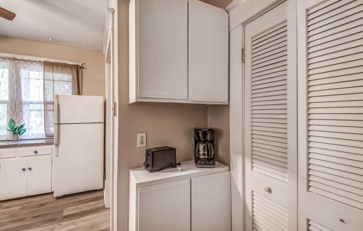 A compact kitchen with white cabinets, a toaster, and a coffee maker on a countertop.