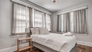 Ein Schlafzimmer mit Bett, Nachttisch und Vorhängen.