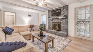 Una sala de estar con chimenea, un sofá, una mesa de centro y un ventilador de techo.