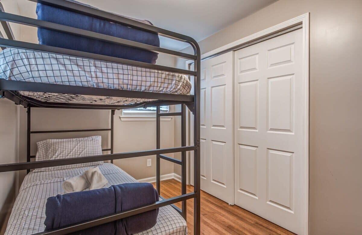 A bunk bed room with a window, a white door, and a wooden floor.