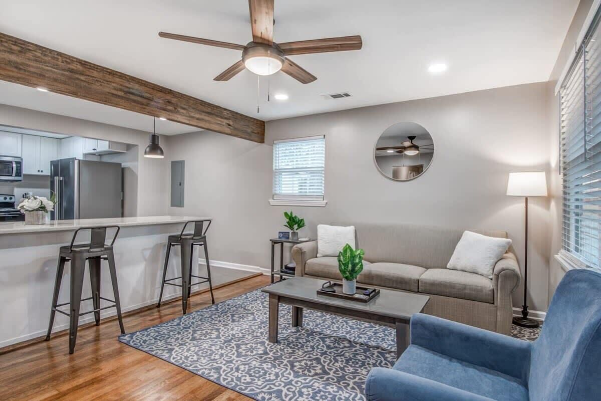 A modern kitchen with a central island, bar stools, a sofa, and a coffee table.