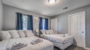 A room with two beds, a door, and a window with curtains.