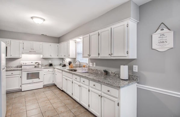 A kitchen with white cabinets, a granite countertop, and a wall-mounted sign.