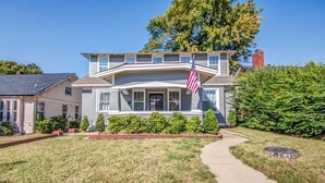 A two-story house with a front porch, an American flag, and a well-maintained lawn. - Glenview Guesthouse (Memphis)