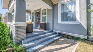 A two-story house with a covered porch, steps leading to the entrance, and a large window on the right side. - Glenview Guesthouse (Memphis)