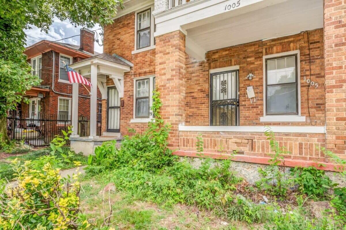 A two-story brick building with a porch and a flag.