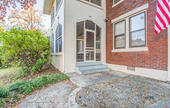 A two-story building with a brick facade, a white door with the number 243, and a small front garden. - Avalon Nest Upstairs (Memphis)