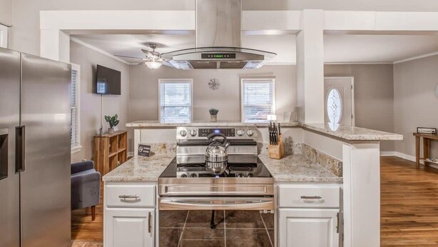 A modern kitchen with stainless steel appliances, a central island, and a large range hood. - Flamingo Hideaway (Memphis)