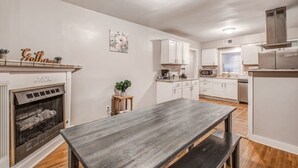 A modern kitchen with white cabinets, a built-in stove, and a dining area with a wooden table and benches. - Flamingo Hideaway (Memphis)