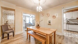 A dining area with a wooden table and benches, a chandelier, and a stone wall. - Garland Haven Hideaway Unit A (Memphis)