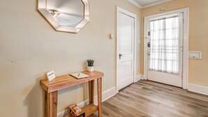 A hallway with a wooden console table, a mirror, a door, and a window with curtains. - Garland Haven Hideaway Unit A (Memphis)
