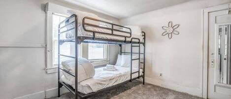 Habitación con literas, una ventana, una puerta y un adorno en la pared.