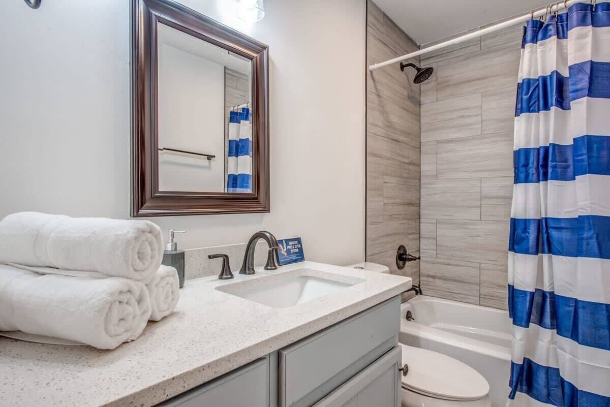 A bathroom with two sinks, a mirror, a shower, and a toilet.