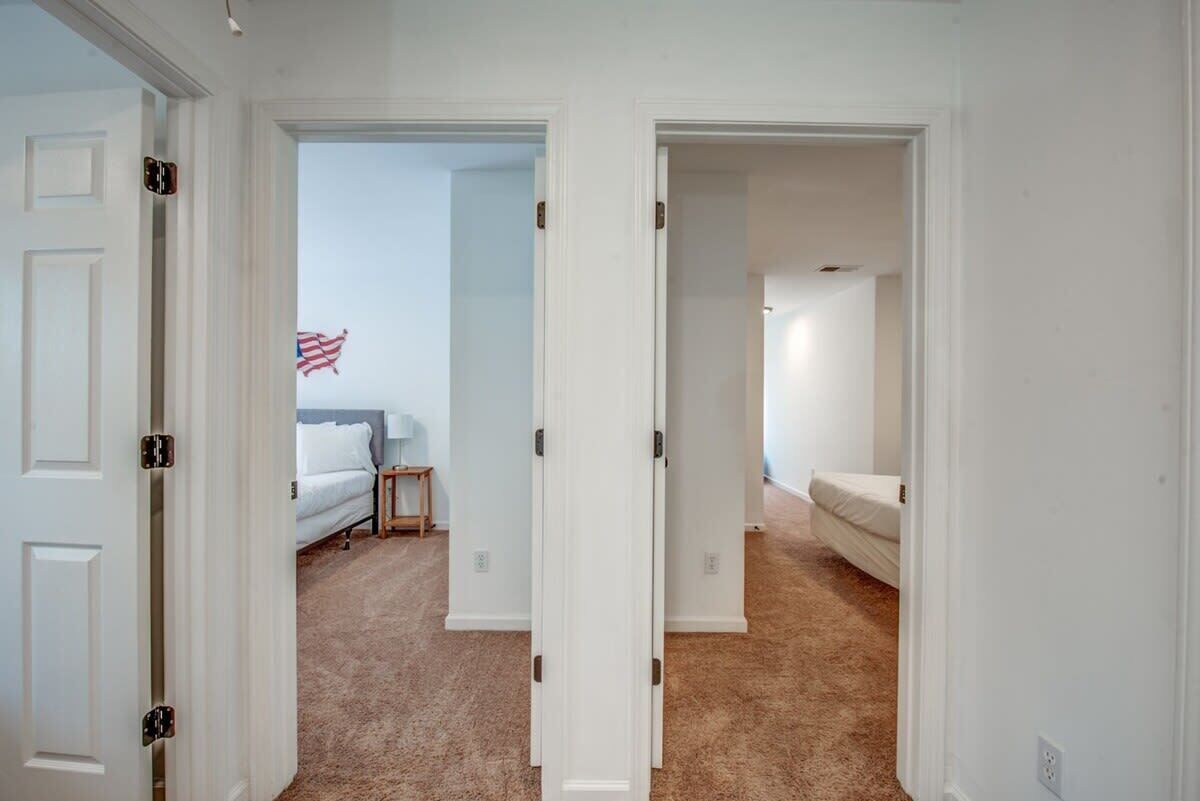 A hallway with two bedrooms, each with a bed and a nightstand.