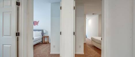 A hallway with two bedrooms, each with a bed and a nightstand.