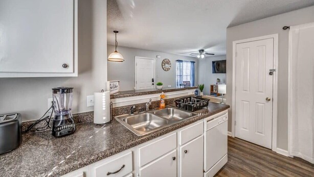 A kitchen with granite countertops, stainless steel appliances, and white cabinetry. - Cedar Ave Escape (Memphis)