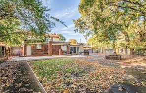 A backyard with a brick house, a barbecue area, and a patio with chairs. - Warrington Nook (Memphis)