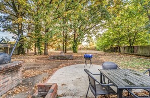 A backyard with a concrete patio, a table and chairs, a barbecue grill, and a wooden fence. - Warrington Nook (Memphis)