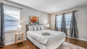 Una camera da letto con un letto, due comodini, un quadro appeso al muro e una finestra con tende.