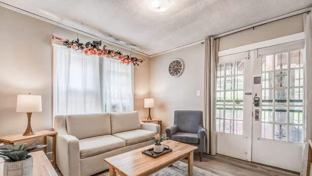 A living room with a sofa, armchair, coffee table, and a door with glass panels.
