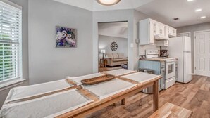 Una cucina moderna con mobili bianchi, forno a incasso e zona pranzo con tavolo e panche in legno.