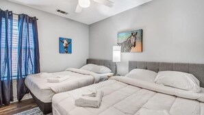 Una camera d'albergo con due letti, una ventola a soffitto e opere d'arte alle pareti.