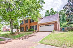 A two-story brick house with a garage, a driveway, and a well-maintained lawn.