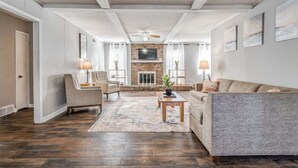 A spacious living room with a fireplace, a sofa, a coffee table, and two lamps.