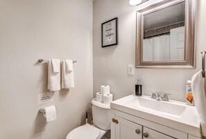 A bathroom with a toilet, sink, and mirror. There are towels hanging on a rack, a framed quote on the wall, and a sign indicating the bathroom is for guests only. - Flowering Peach Stayhouse (Memphis)