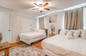A bedroom with two single beds, a ceiling fan, a nightstand with a lamp, and a door. - Flowering Peach Stayhouse (Memphis)