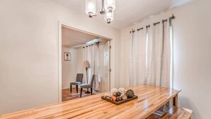 Uma mesa de jantar de madeira com um banco, uma luminária e objetos decorativos sobre a mesa.