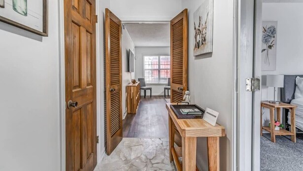 A hallway with wooden doors, a small table with a tray, and artwork on the walls. - Tulip Tree Cottage (Memphis)