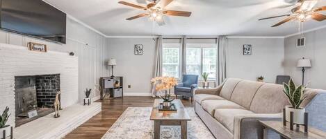 A living room with a fireplace, a sofa, a coffee table, and ceiling fans.
