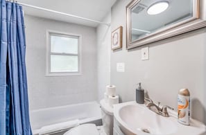 Un baño con bañera, lavamanos, inodoro y ventana.