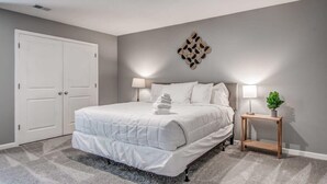 Ein Schlafzimmer mit einem großen Bett, zwei Nachttischlampen, einem Holznachttisch und einem dekorativen Wandbild.