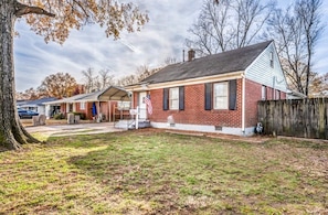 A single-story brick house with a front porch, a garage, and a wooden fence. - Parnassus Cottage (Memphis)