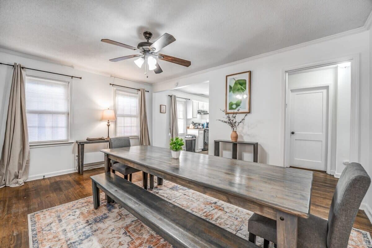A dining area with a wooden table, benches, a ceiling fan, and a rug.