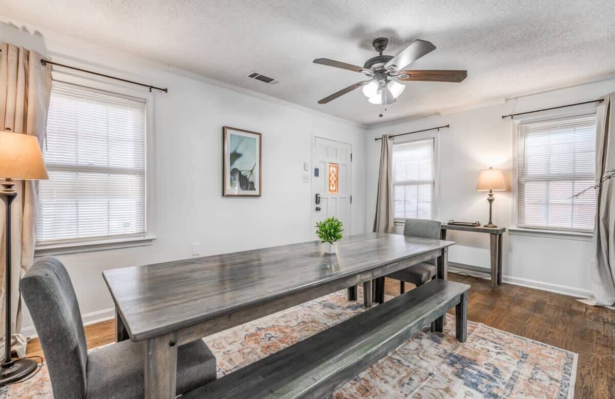 A dining area with a wooden table, benches, a ceiling fan, and a rug.